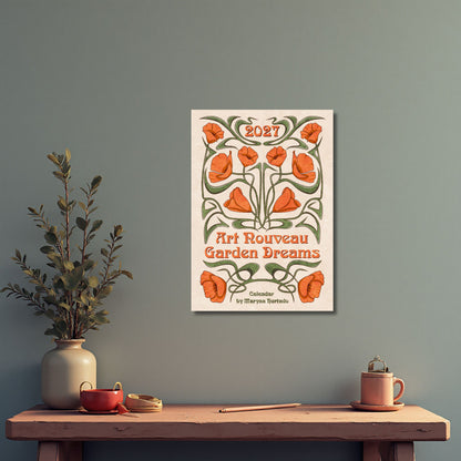 Art Nouveau Garden Dreams calendar hanging on a gray-green wall above a shelf with a plant