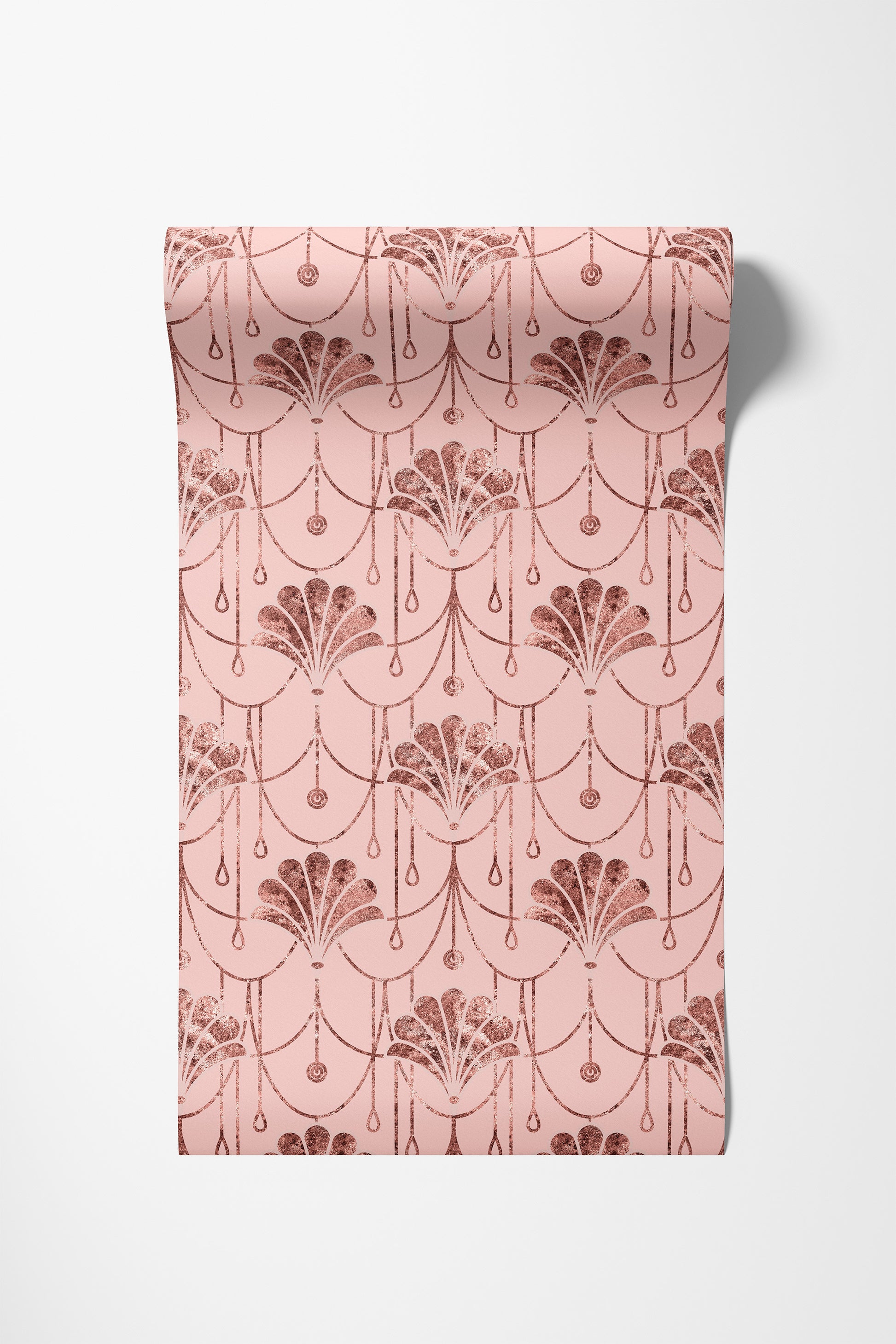 A roll of wallpaper with a repeating Art Deco fan and scallop pattern in rose gold on a light pink background, shown against a neutral light gray background.