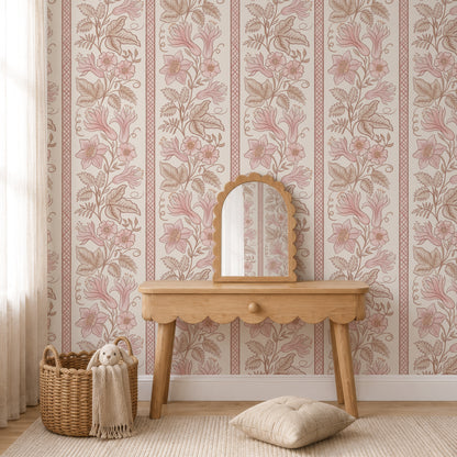 A styled interior scene showing floral wallpaper with vertical pink and beige botanical stripes, a light wood console table, a matching arched mirror, a woven basket with a cream throw and plush toy, and a beige cushion on a rug.