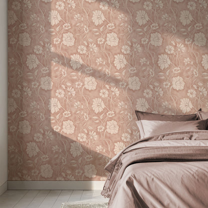 A styled bedroom corner showing a bed dressed in dusty mauve bedding against a wall with matching floral wallpaper and soft window-shadow lighting.