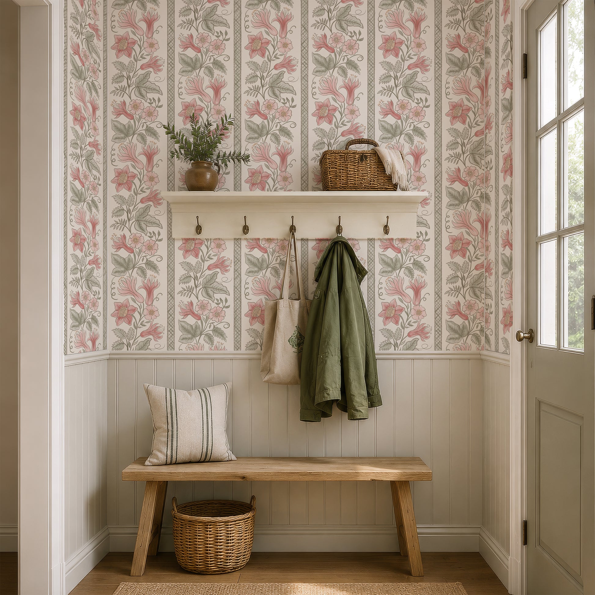 A styled entryway with floral wallpaper, a wooden bench, a white shelf with hooks, a green jacket hanging on a hook, a tote bag, a basket, and a door on the right.