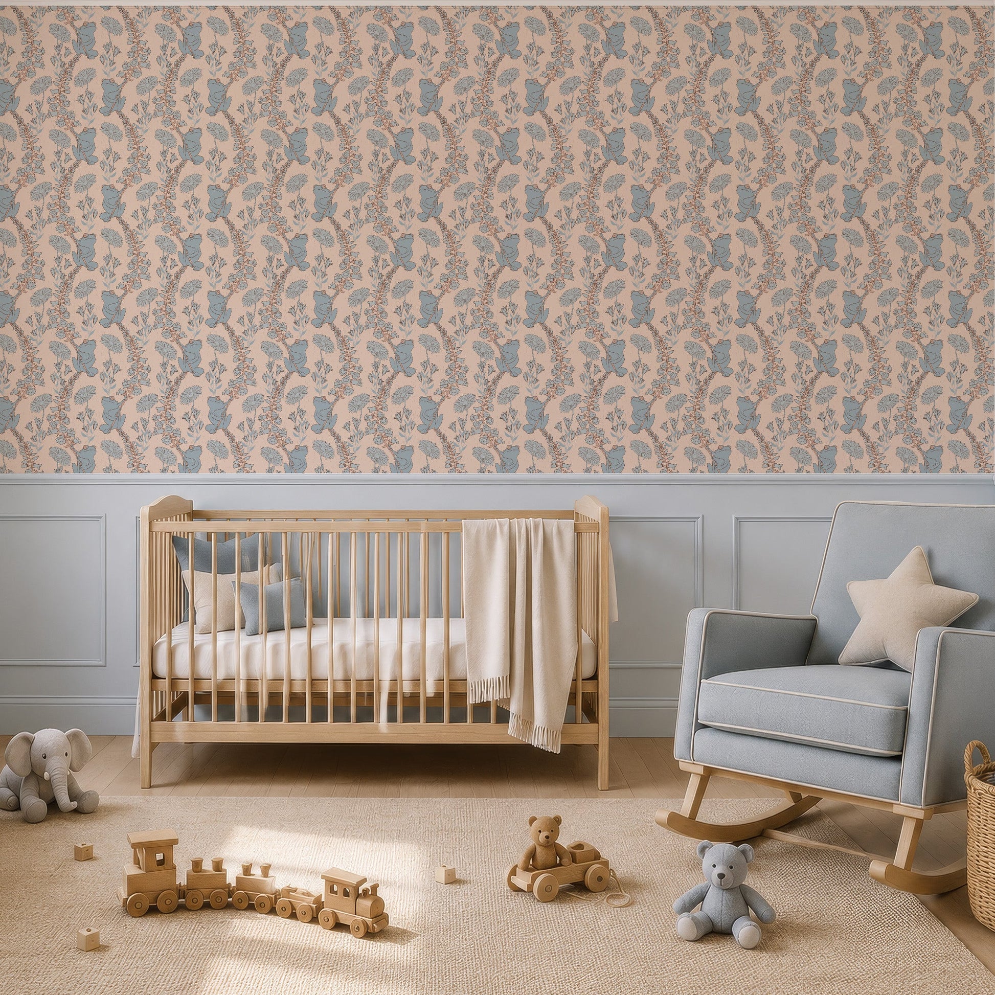 A styled nursery room featuring a wall covered in a beige and dusty blue frogs  wallpaper, with a light blue crib, matching rocking chair, and a light blue dresser.
