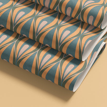 Rolled patterned wallpaper shown on a warm beige background. The wallpaper has a repeating mid-century style ogee  motif in teal blue, butter yellow, and pale blush 