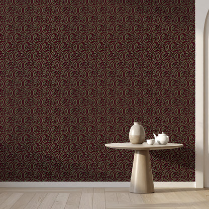 Dark brown and sage ogee patterned wallpaper shown on a wall in a styled room setting with a light wood floor and a small round table holding a vase and teapot.