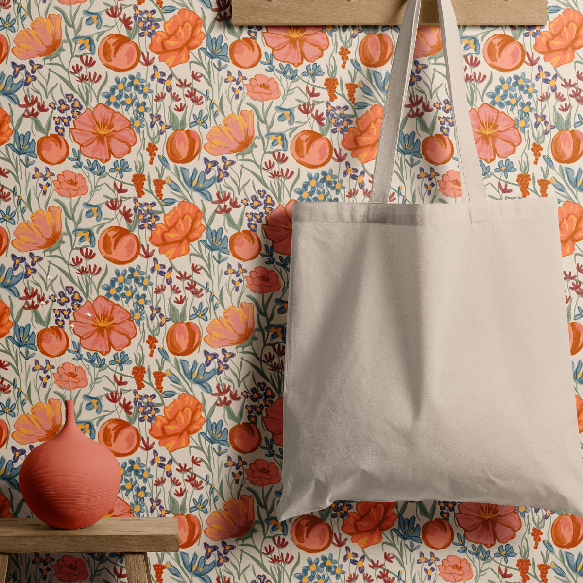 Cream floral wallpaper with peach and orange flowers behind a canvas tote bag