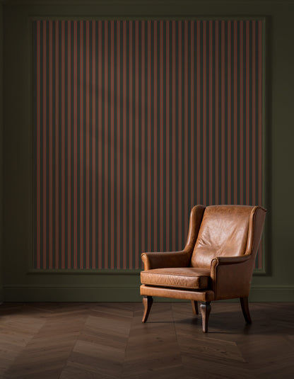 Brown leather armchair in a room with a striped wall and wooden floor.